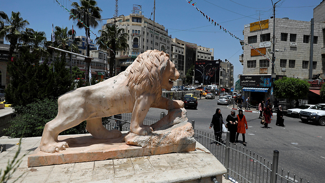 פלסטינים עוברים ליד פסל האריה ברמאללה (צילום: רויטרס)