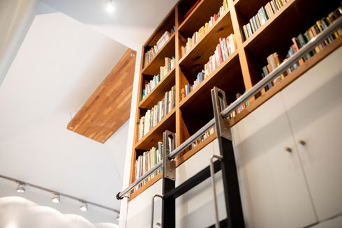 מאחר שהמקום מצומצם, הספרייה מוקמה בנישה מעל המקרר, עם סולם כמו בחנות בגדים (צילום: תומס סולינסקי)