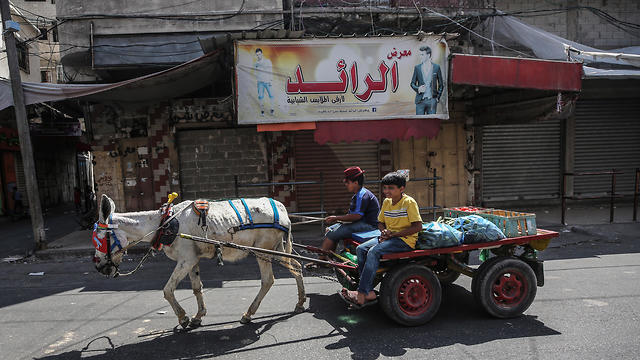 Palestinians vendor ride a cart and pass by shops closed during a general strike in Gaza City due to Bahrain summit (Photo: EPA)
