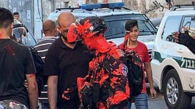 A police officer is covered in red paint during clashes in Issawiya
