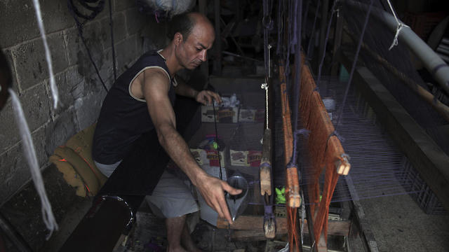 Palestinian worker weaves carpets on a traditional wooden loom at a carpets factory in Gaza City (Photo: AP)