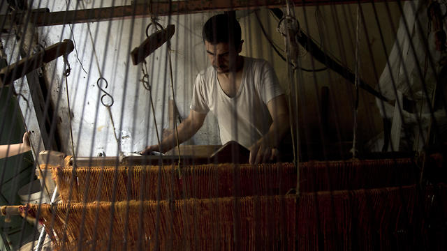 Palestinian worker weaves carpets on a traditional wooden loom at a carpets factory in Gaza City (Photo: AP)