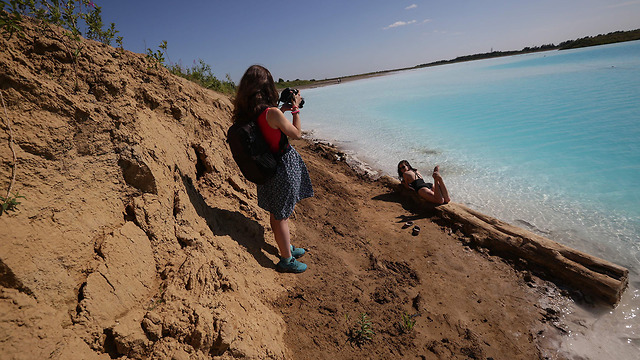 אנשים מצטלמים ב אגם טורקיז פסולת רעילה מפעל סיביר רוסיה (צילום: AFP)
