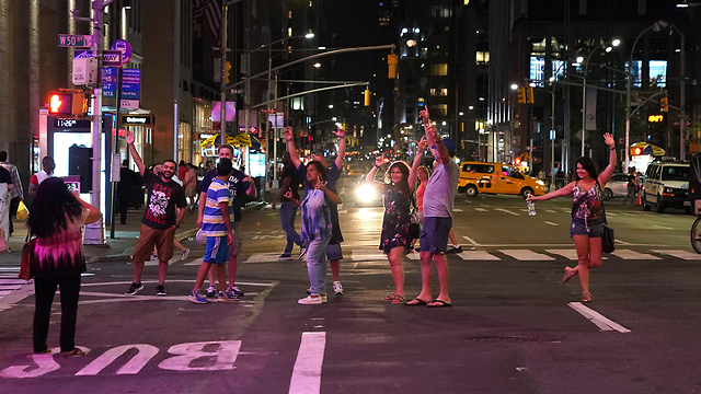 אנשים חוגגים בשדרה השישית אחרי שהחשמל חזר בניו יורק (צילום: AFP)