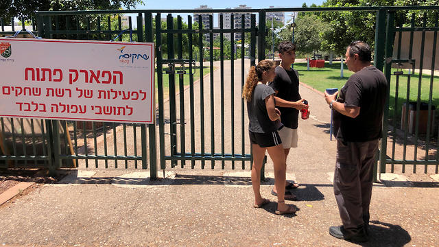 A security guard checks the identification of visitors near the entrance to a park in Afula