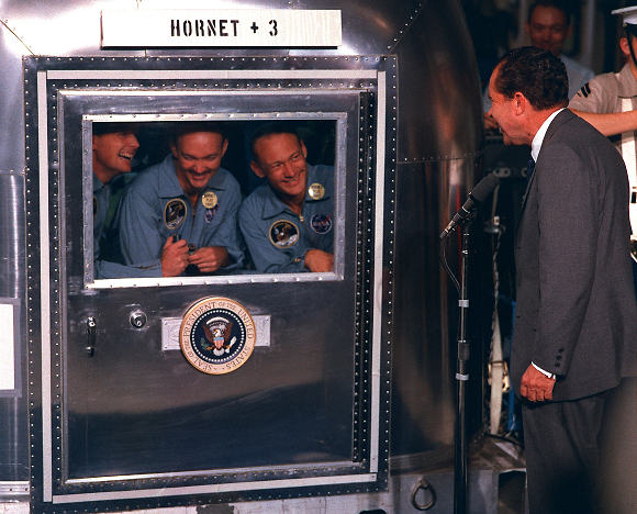 שלושה שבועות בהסגר. הנשיא ניקסון מברך את האסטרונאוטים בתא הבידוד על סיפון ה"הורנט" (צילום: נאס"א)