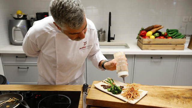 A chef prepares a dish including a piece of lab-grown steak produced from cow cells by Israeli company Aleph Farms