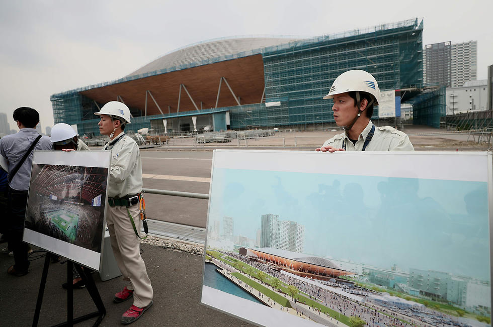 פועלים מציגים אילוסטרציית אצטדיון באולימפיאדת טוקיו 2020 (צילום: AFP)
