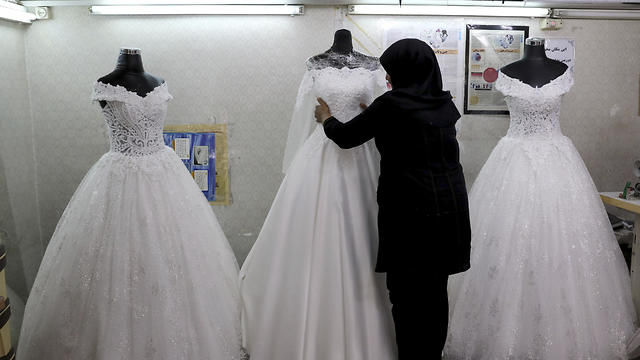 A worker adjusts a display of wedding dresses in downtown Tehran, July 3, 2019