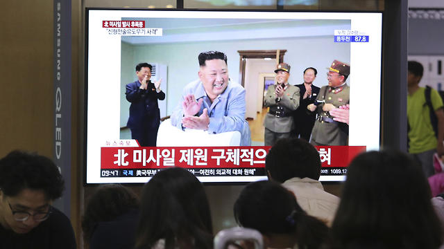 קים מחייך ומוחא כפיים על מסך הטלוויזיה בצפון קוריאה (צילום: AP)