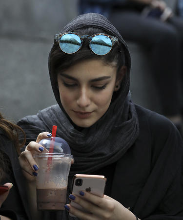 An Iranian woman uses her cell phone outside a shopping mall in northern Tehran, July 2, 2019 