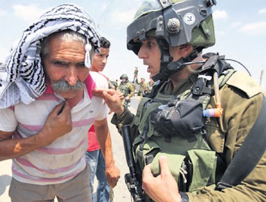 A resident of Fasayil talks to an IDF soldier during the weekly protests over the village's lack of electricity 