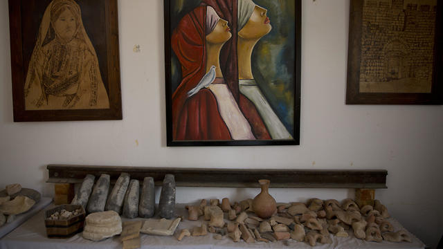 In this July 17, 2019 photo, paintings decorate the wall over ancient artifacts displayed inside Al-Qarara private museum in town of Khan Younis
