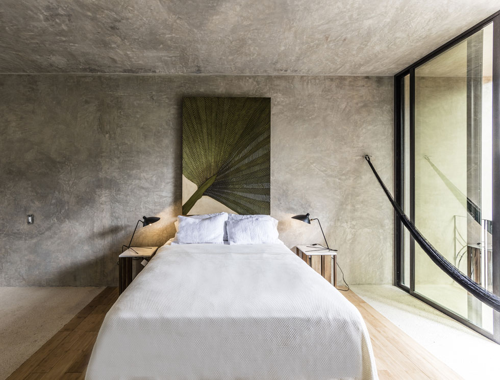 חדר השינה של בעלי הבית עטוף בבטון, כמו כל החלק החדש של הבית, למעט שטיח עץ נעים למדרך, מתחת למיטה וסביבה (צילום: Taller Estilo Arquitectura)