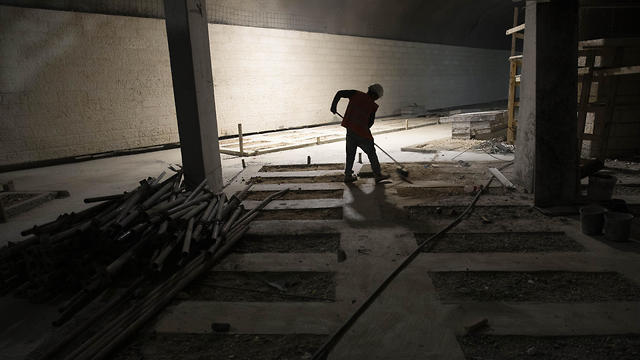 A worker cleans the floor at the construction site of a massive underground cemetery in Jerusalem, August 18, 2019  