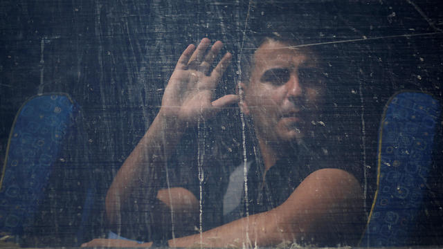 A Palestinian man waves from a bus as he leaves Gaza (Photo: Reuters)