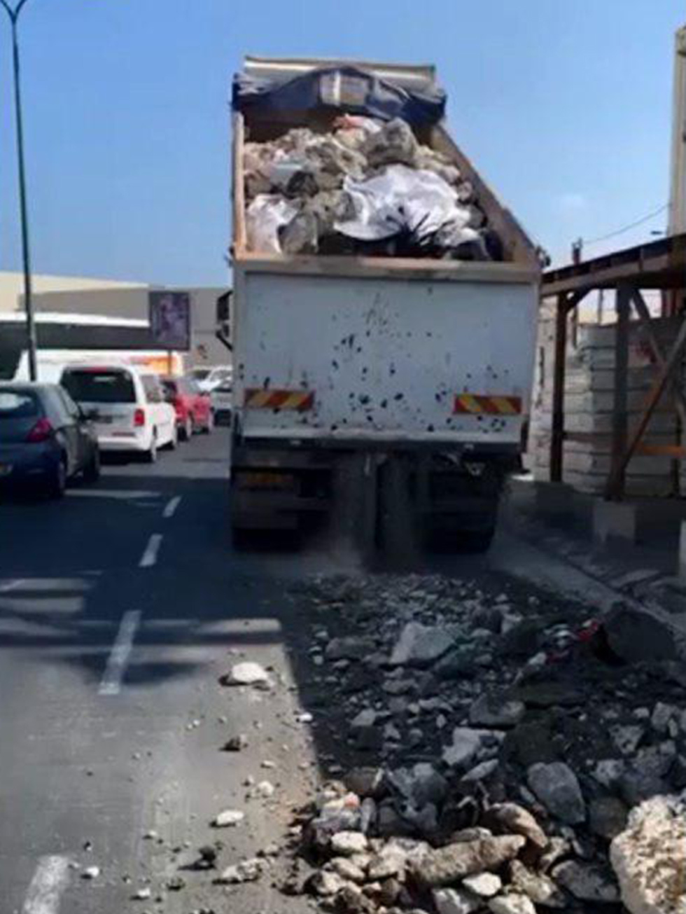 נהג משאית פרק על הכביש פסולת בניין מסוכנת באתר בנייה סמוך לנמל תל אביב ()