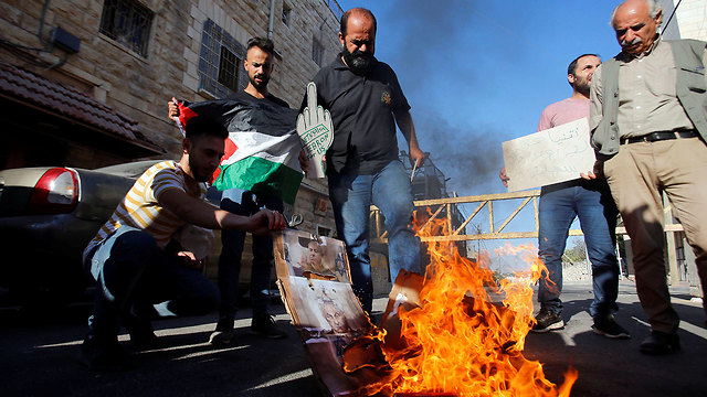 Palestinians burn Netanyahu's photo during his visit to Hebron (Photo: Reuters)