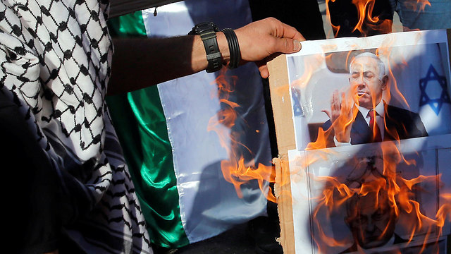 פעילים פלסטינים מציתים את תמונת בנימין נתניהו בחברון (צילום: רויטרס)