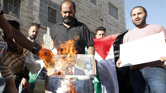 פעילים פלסטינים מציתים את תמונת בנימין נתניהו בחברון (צילום: EPA)