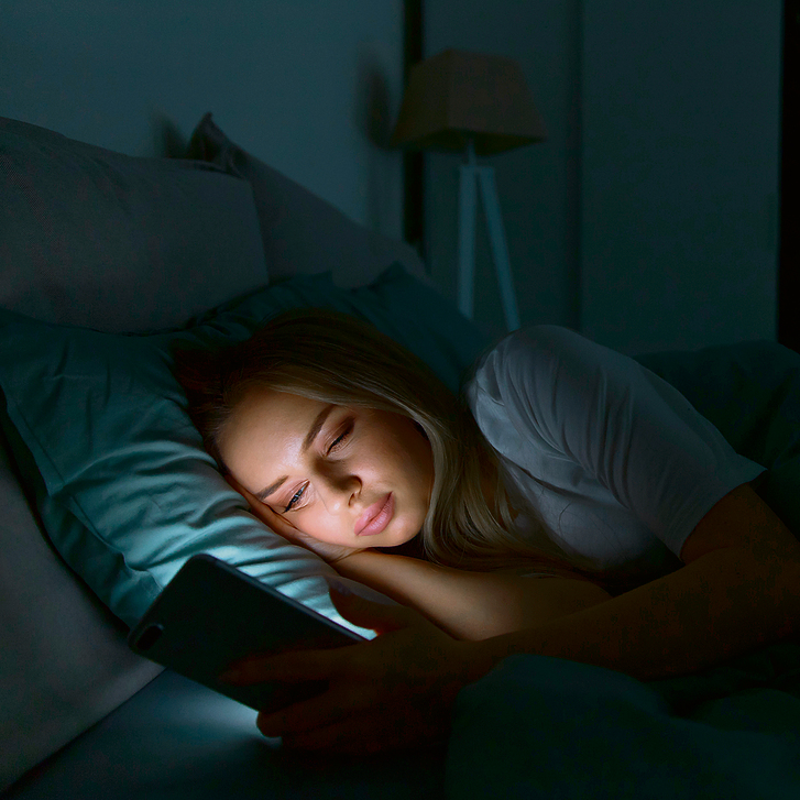 במיטה עם הטלפון. האור הכחול דוחה את האיתות הטבעי למוח, לפיו הזמן לישון מתקרב