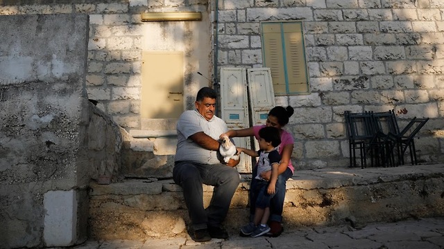 Musleh holds a rabbit as he spends time with his daughter and grandson in his yard (Photo: Reuters)