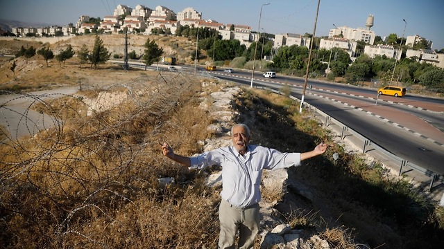 Farun gestures by a road in al-Eizariya with Maale Adumim in the background (Photo: Reuters)