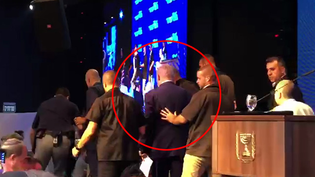 Netanyahu being rushed by his security guards off stage in Ashdod