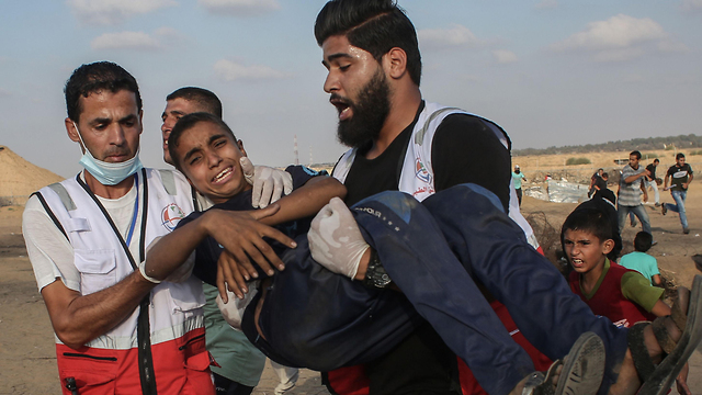 Palestinian medics evacuating a youth wounded during clashes with IDF troops on the Gaza border  (Photo: AFP)