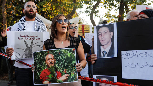 Palestinians demonstrate with signs in support of, and with the pictures of Samer al-Arbeed