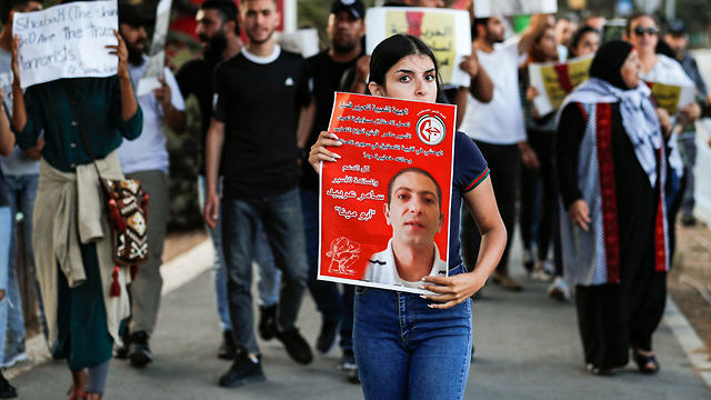Palestinians demonstrate with signs in support of, and with the pictures of Samer al-Arbeed