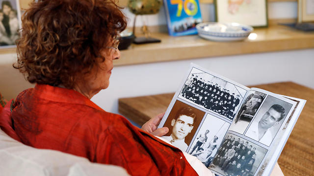 Nadia, widow of Israeli spy Eli Cohen, looks at photographs depicting her late husband during an interview 