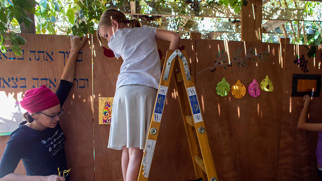 Noemie Stanleigh and her daughters decorate their sukka (Photo: Reuters)