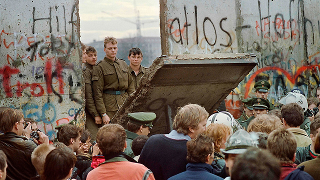 אנשים במערב ברלין מול שבר בחומה ומהצד השני חיילים ממזרח ברלין (צילום: AFP)