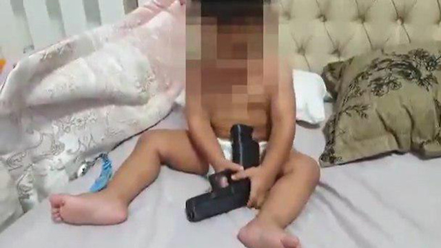 אום אל פחם: אבא נותן לתינוק שלו לשחק באקדח ()