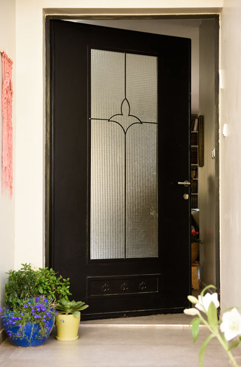 דלת הכניסה הסטנדרטית שהייתה צבועה באדום ובסגנון מיושן הוחלפה תוך הגדלת הפתח בדלת ברזל גדולה  (צילום: תהילה זוסמן)