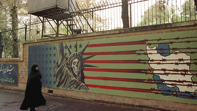 An Iranian woman walks past an anti-U.S. mural at the former American embassy in Tehran, Nov. 3, 1999 