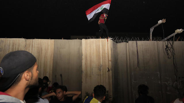 Protester waves Iraqi flag on wall of Iranian consulate in Karbala