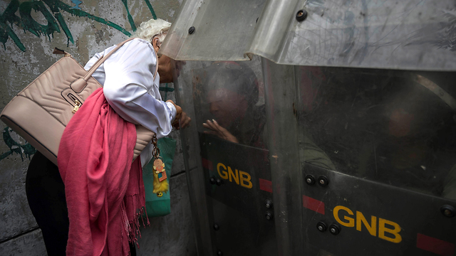 An elderly woman talks with soldiers blocking access to an opposition demonstration in Bolivia, October (Photo: EPA)