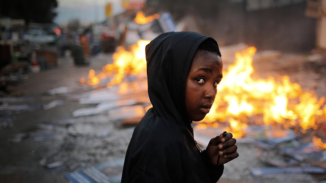 תמונות השנה EPA  2019 ילד ליד אש לחימום משפחות שגורשו מבניין מסחרי שעליו השתלטו דרום אפריקה יוני  (צילום: EPA)