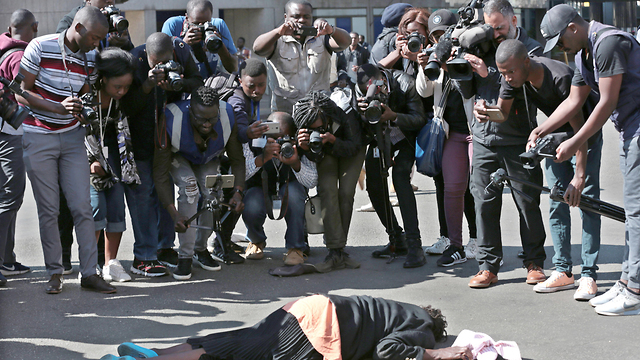 Photographers take pictures of a woman wounded in clashes between protesters and police in Zimbabwe, August (Photo: EPA)