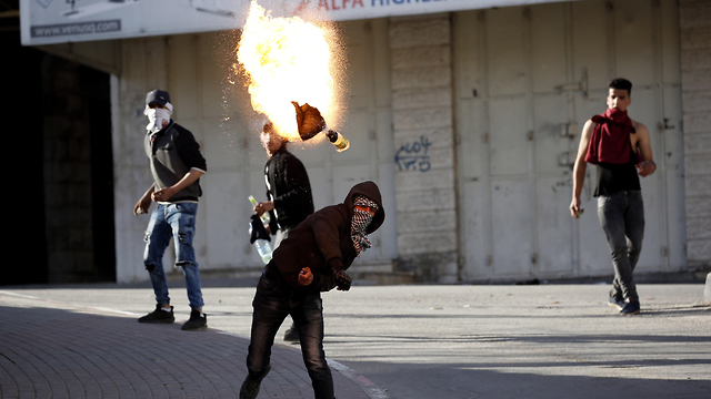 A Palestinian hurling a Molotov cocktail at IDF troops during Hebron unrest, April (Photo: EPA)