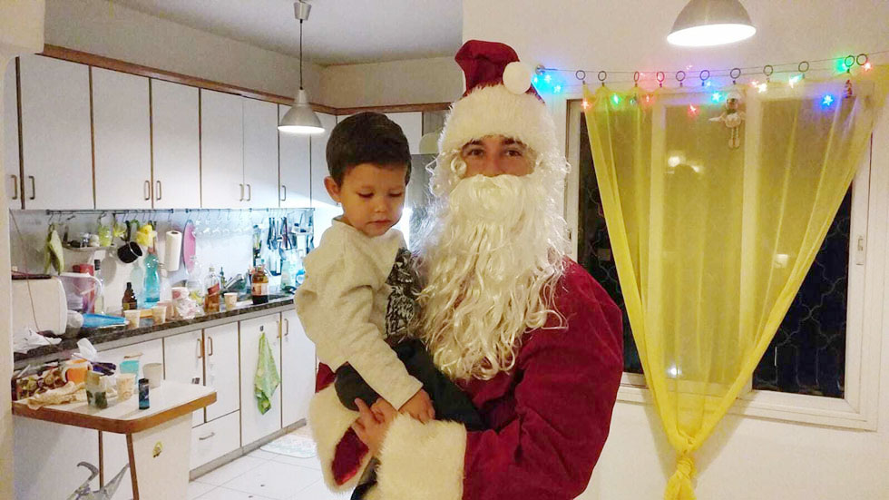 Денис Юнгман в костюме Деда Мороза поздравляет сынишку с Новым годом. Фото из семейного архива