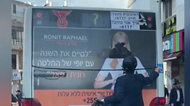 Мужчина замазывает лицо манекенщицы Галит Гутман на рекламном плакате в центре Израиля 