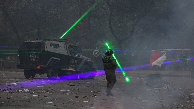 תמונות השנה AP סנטיאגו צ'ילה מפגינים מכוונים קרני לייזר על כוחות הביטחון (צילום: AP)