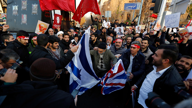 מפגינים שורפים דגלי ישראל ו בריטניה מול שגרירות בריטניה ב טהרן איראן (צילום: EPA)