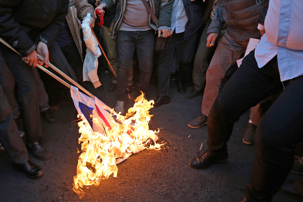 מפגינים שורפים דגלי ישראל ו בריטניה מול שגרירות בריטניה ב טהרן איראן (צילום:  AFP)