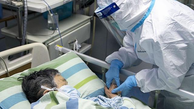 עובד מטפל בחולה ביחידה לטיפול נמרץ בבית החולים ז'ונגנן בסין ()