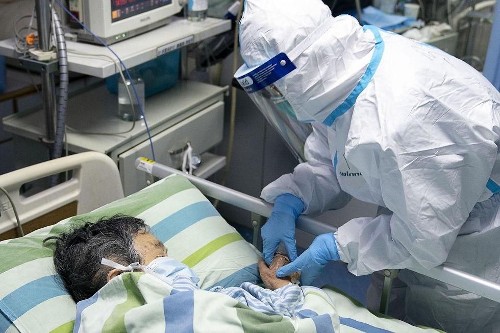 עובד מטפל בחולה ביחידה לטיפול נמרץ בבית החולים ז'ונגנן בסין ()