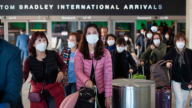 אנשים אסייתים עם מסיכות מגיעים לשדה תעופה ב לוס אנג'לס  (צילום: AFP)